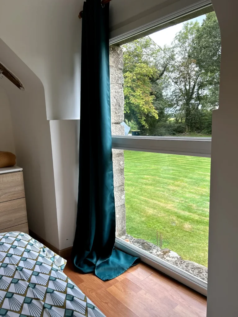 Chambre du gîte avec grande fenêtre donnant sur le jardin